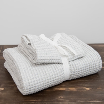 Sett med blåaktiggrå-hvitt håndklær er bundet med et bredt bånd