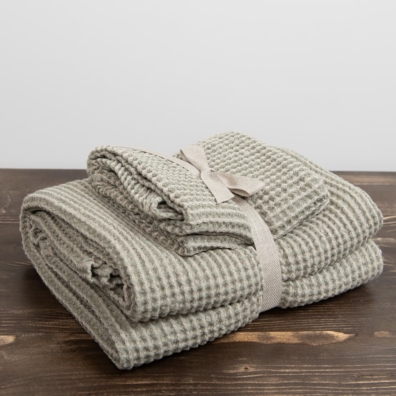 Sett med beige-grønnlig håndklær er bundet med et bredt bånd