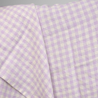 Linstoff med lyse lilla ruter vasket for å sy klær og hjemmetekstiler
