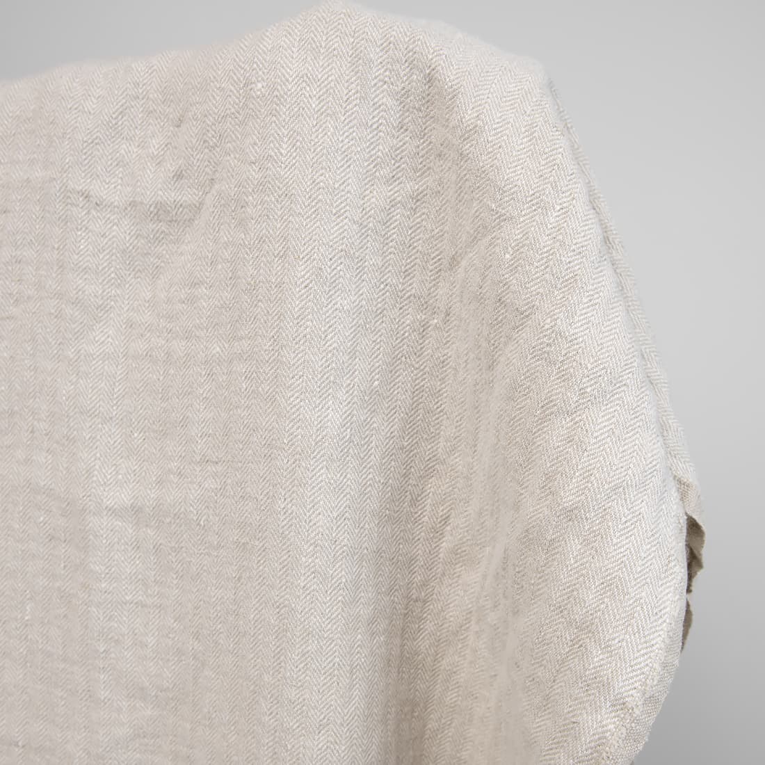 Kraftig linstoff i "fiskebensmønster" vevd av naturlig farge (ufarget, brungrå) og hvitt garn, vasket