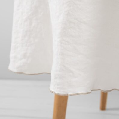 Rund hvit lin duk med dekorativ tett lysebrun søm rundt