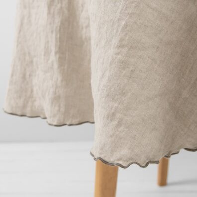 Rund naturlig grå lin duk med dekorativ tett mørkegrå søm