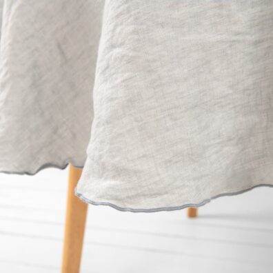 Rund lysegrå lin duk med dekorativ tett mørkegrå søm rundt