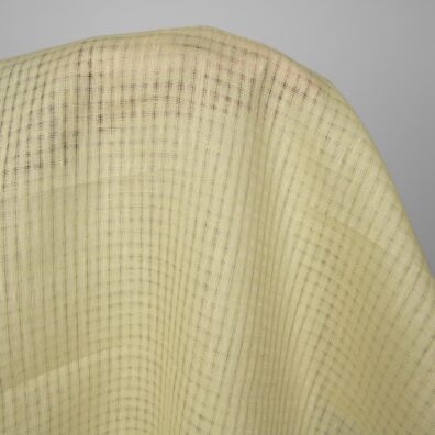 Grønnlig-gult linstoff i gjennomsiktige ruter for sying klær, hjemmetekstiler