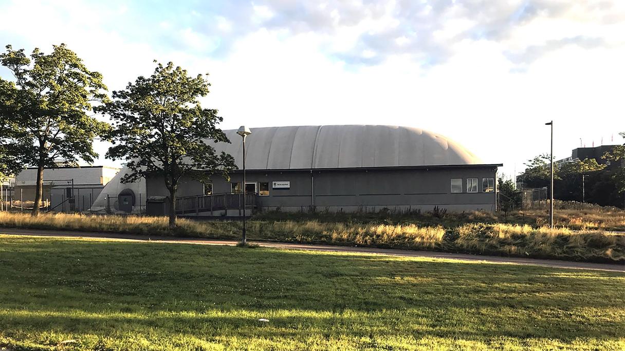 Mörkgrå sporthall med rundat tak.