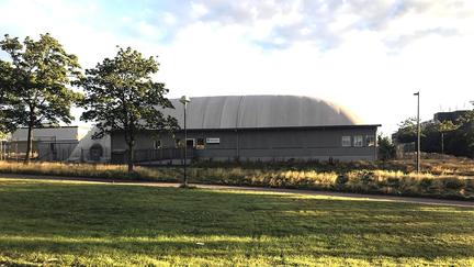 Mörkgrå sporthall med rundat tak.