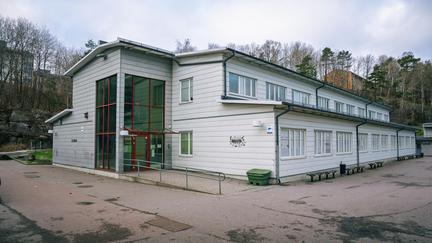 En stor vit skolbyggnad med en röd entré.