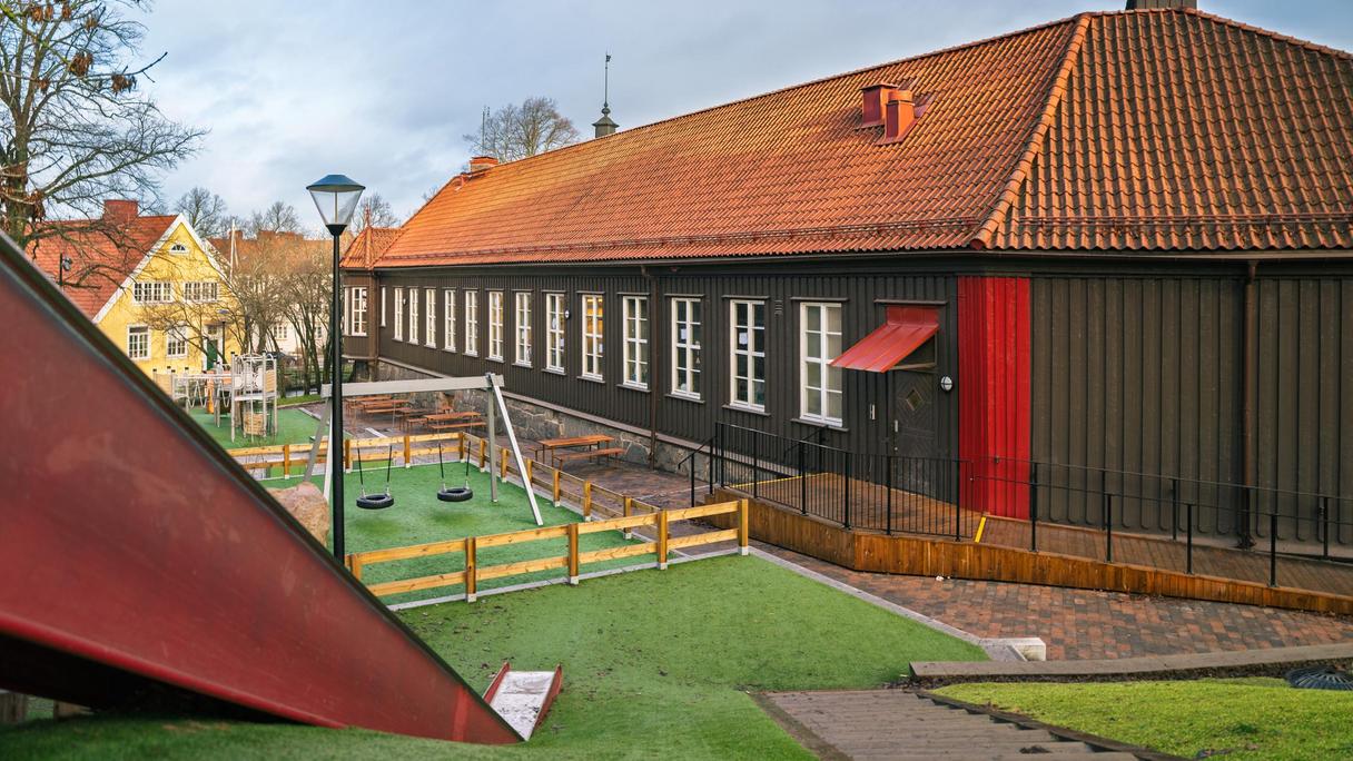 En rutschkana utanför Bagaregårdsskolan. Några gungor och skolbyggnaden kan ses i bakgrunden.
