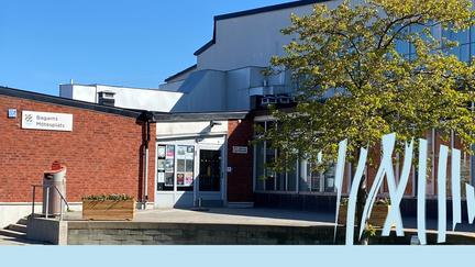 Framsidan och entré på Bagarns mötesplats, med grönt gräs och gröna träd.