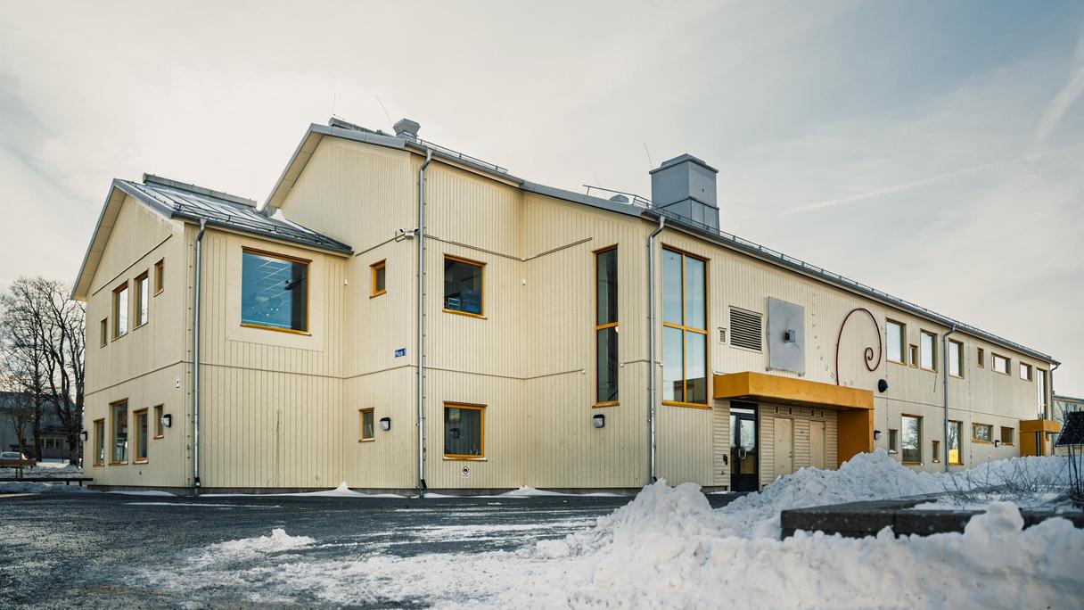 En överblick av Bergumsskolan med ett träd och några snöhögar i bakgrunden.