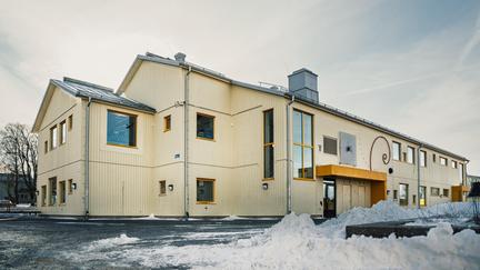 En överblick av Bergumsskolan med ett träd och några snöhögar i bakgrunden.