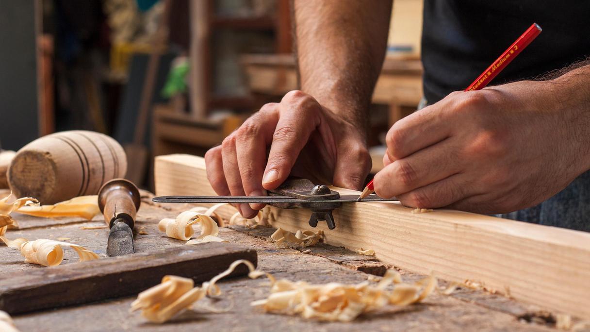 En person tillverkar föremål i snickeriet.