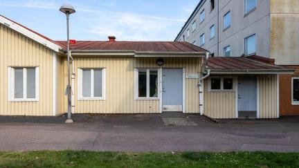 Bilden föreställer en gul byggnad med två gråa dörrar.
