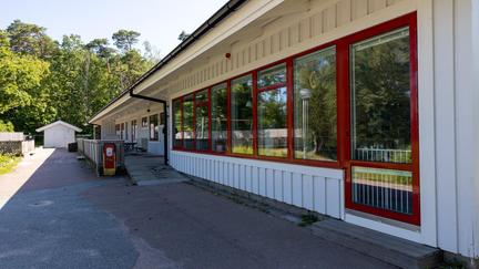 Bilden föreställer en vit byggnad med röda fönsterkarmar.