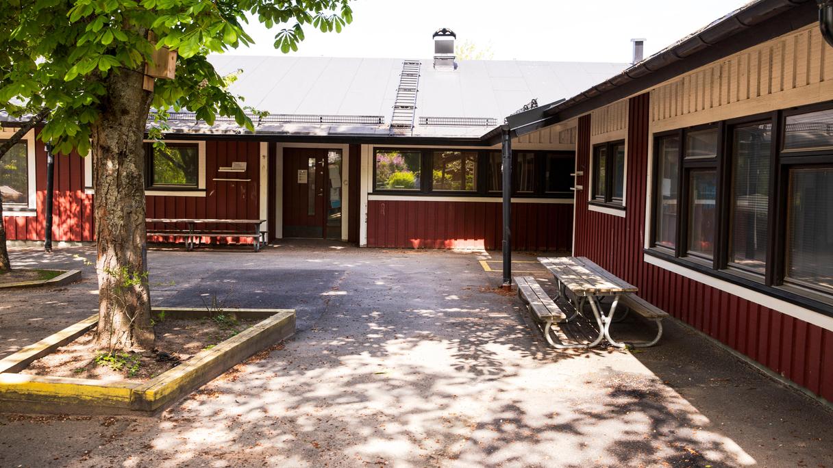 Röd enplansbyggnad i grönska