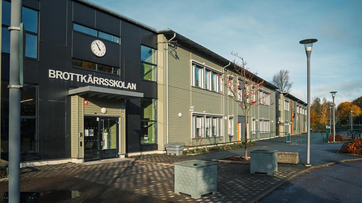 En skolbyggnad med en klocka och texten Brottkärrsskolan på fasaden.