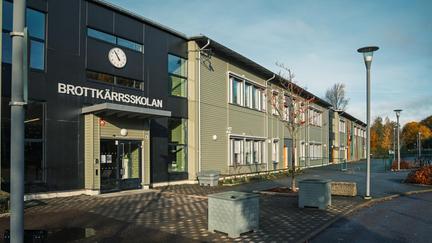 En skolbyggnad med en klocka och texten Brottkärrsskolan på fasaden.