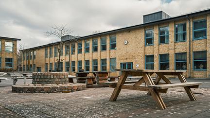 Ett picknickbord framför Brunnsboskolan med några skolbyggnader i bakgrunden.