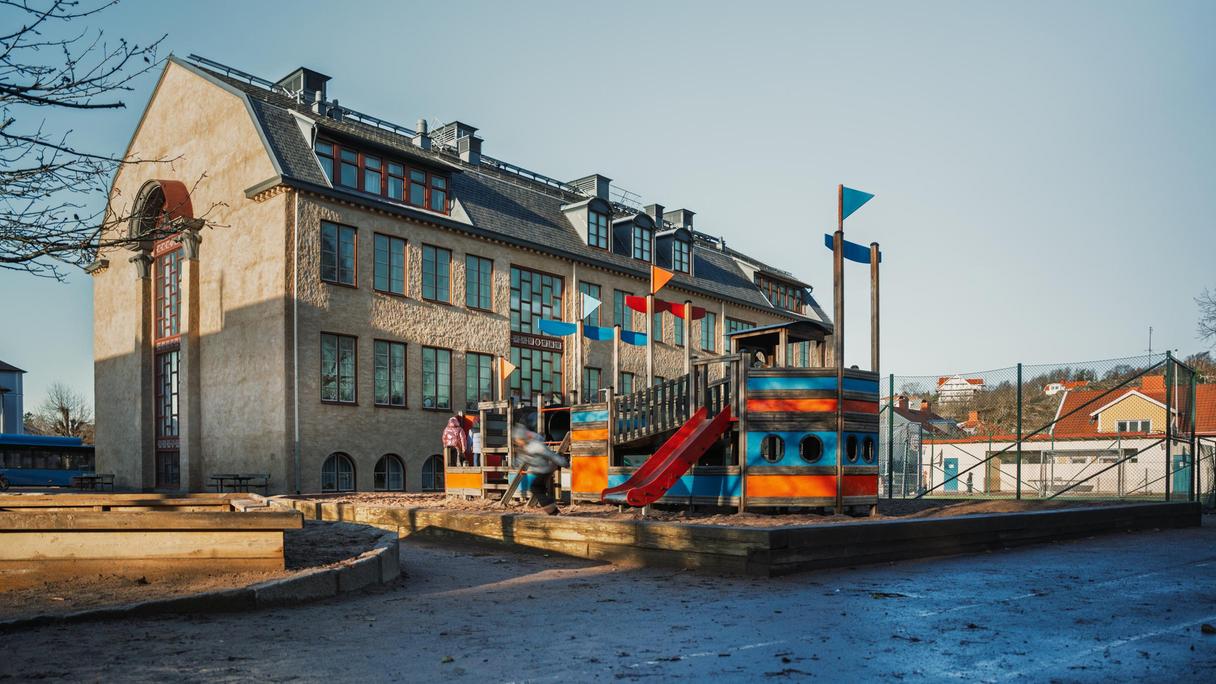 En översikt av Dalaskolan med en lekplats med en rutschkana och en stor klätterställning i fokus. 