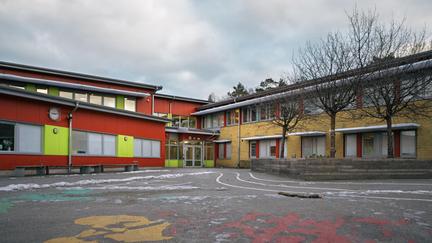 Ellen Keyskolans entré och skolgård med några bänkar och träd i bakgrunden.