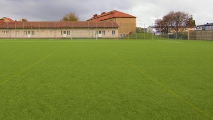 Grön bollplan med byggnader bakom