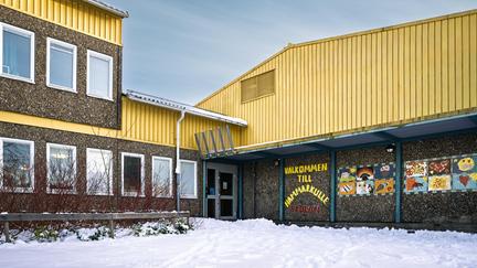 En skolbyggnad med mosaikkonst och texten Välkommen till Hammarkulleskolan på fasaden.