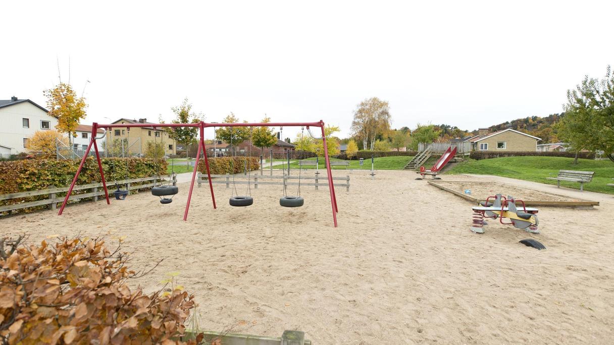 Stor yta av sand med bland annat en gungställning, vippgungor och en rutschkana.
