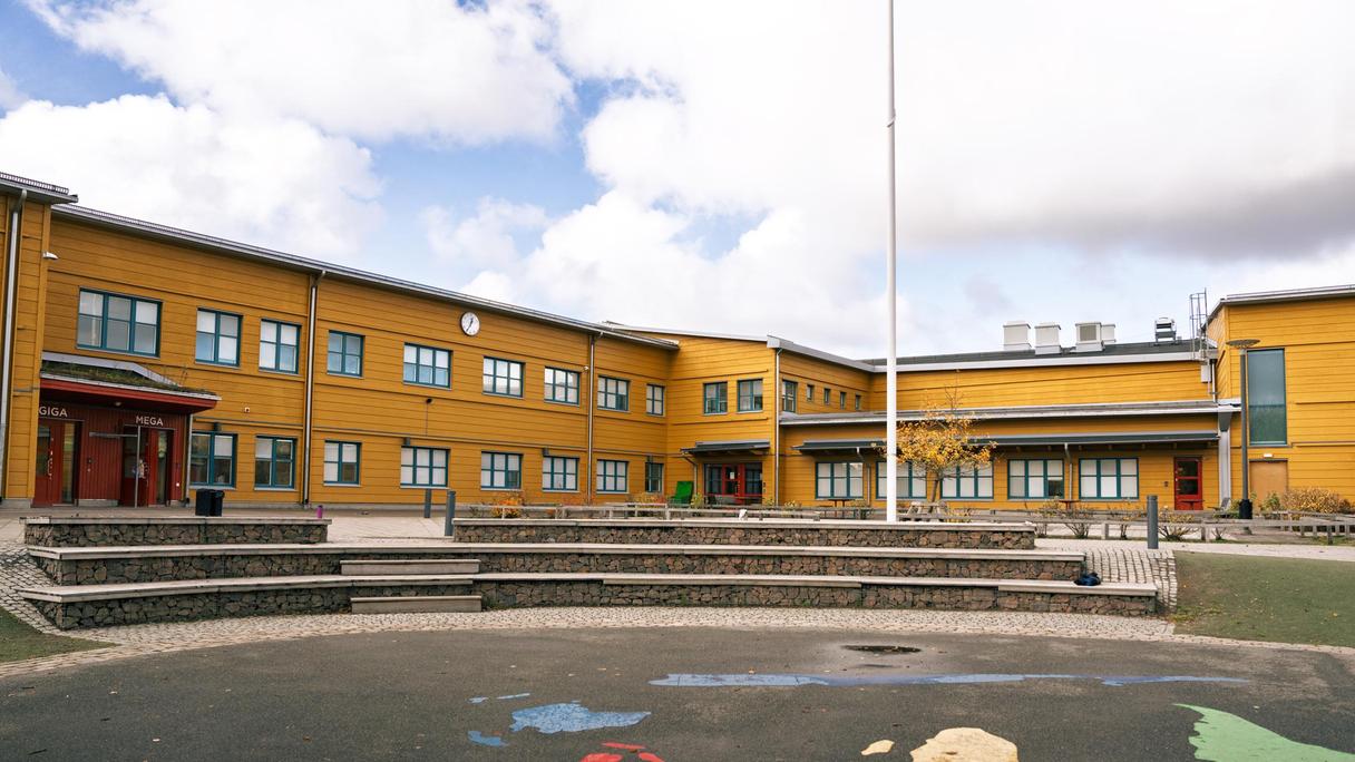 En gul byggnad med trappor som leder upp till den och en gradäng framför.