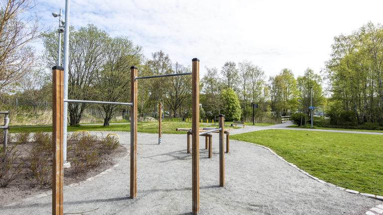 Yta av grus och gräs med ett utegym.
