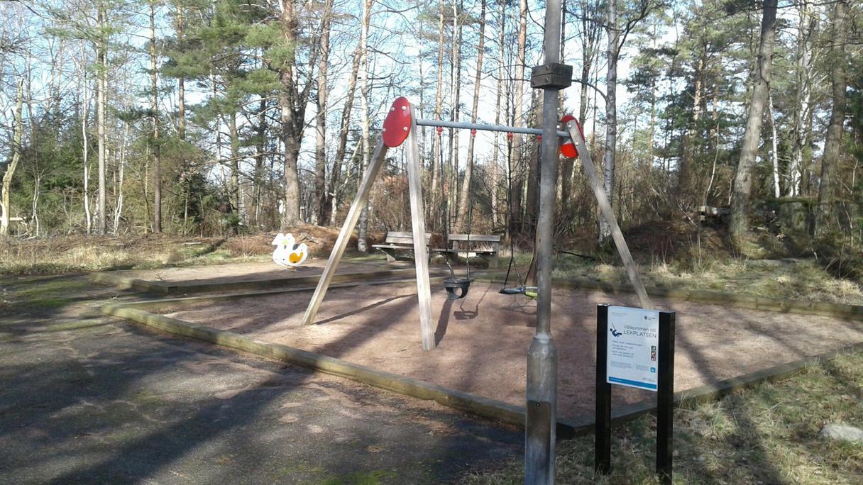 Lekplatsen ligger i ett naturområde med gott om träd som ger skugga och bänkar samt sandlåda med gungor