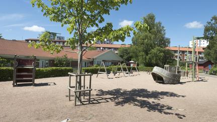 Stor sandyta med bland annat ett gungställning och lekskepp med klätternät.