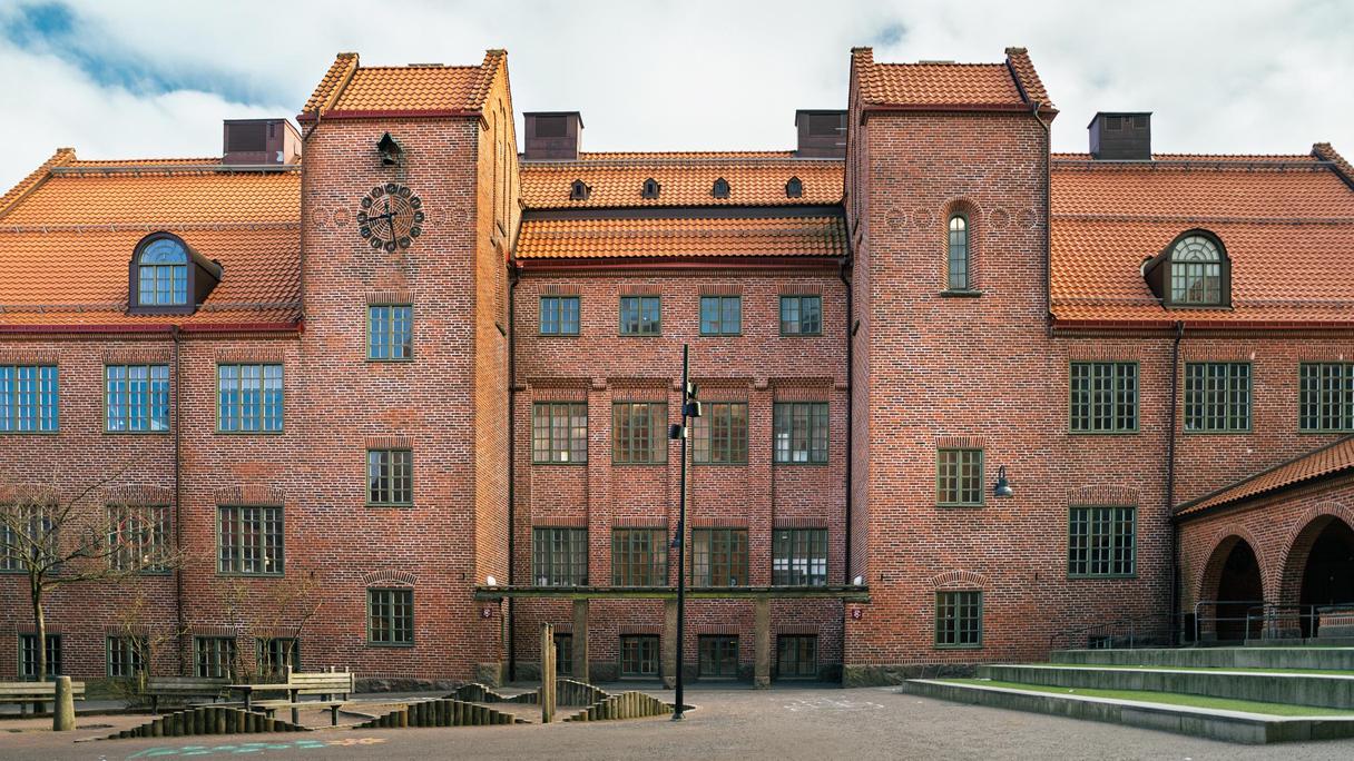 En stor skolbyggnad i rött tegel med en klocka på fasaden.