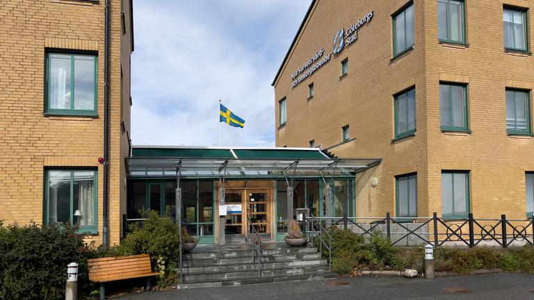 Gula trevåningsbyggnader i en lummig trädgård