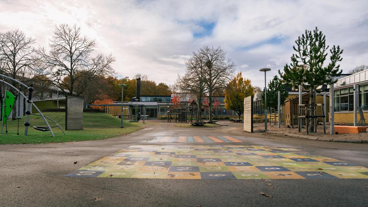 En skolgård i asfalt framför en skolbyggnad.