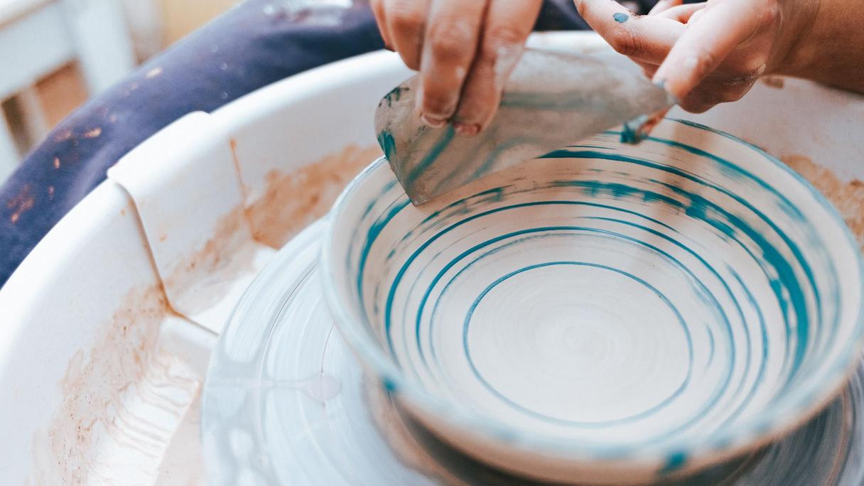 En person målar en blå linje på en keramiktallrik.