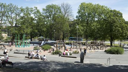 Yta av asfalt och sand med bland annat klätterlek och lekval.