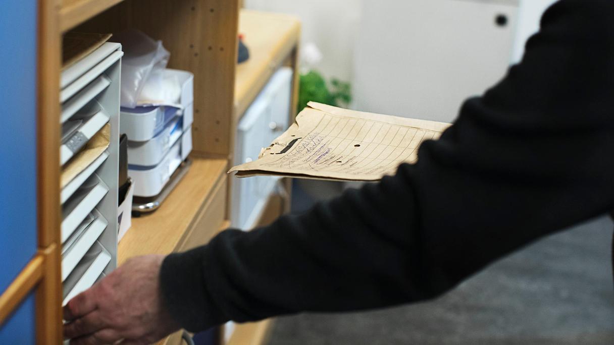 Händer som sorterar brev i postfack.