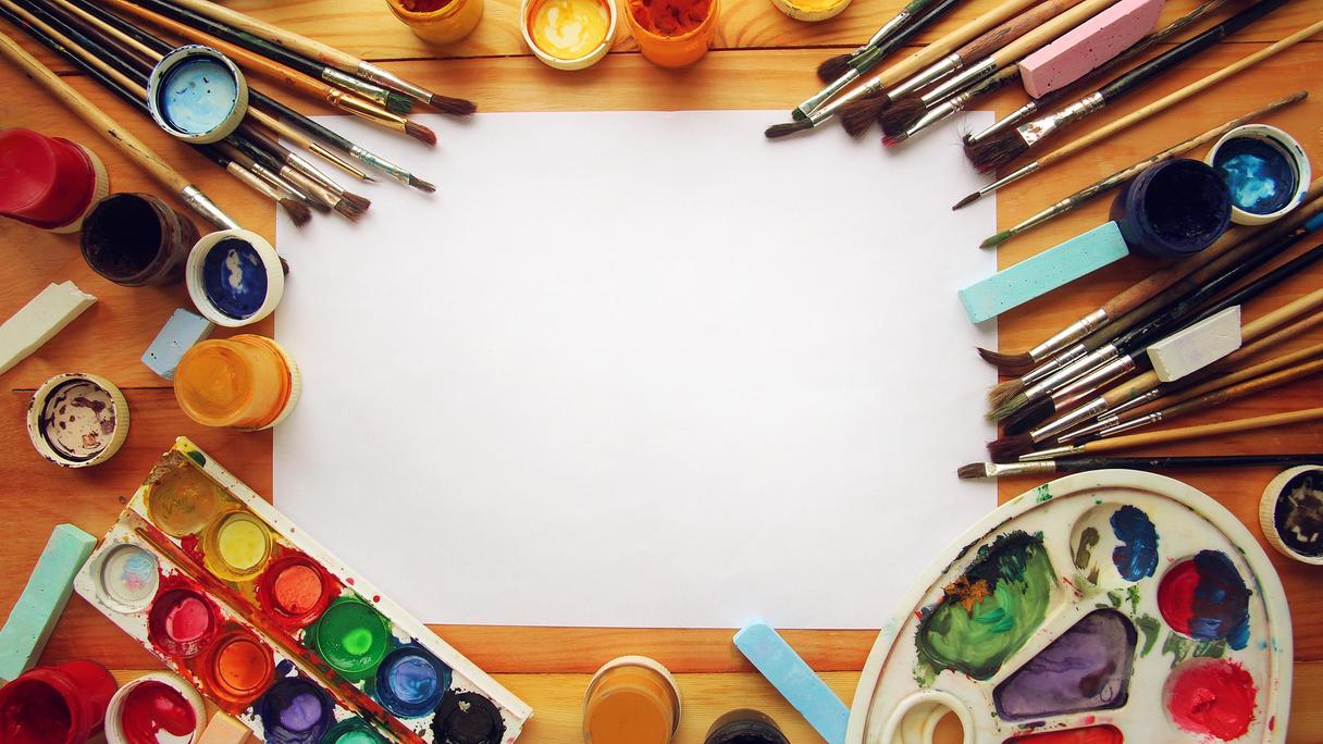 Vitt papper inramat av penslar och färger