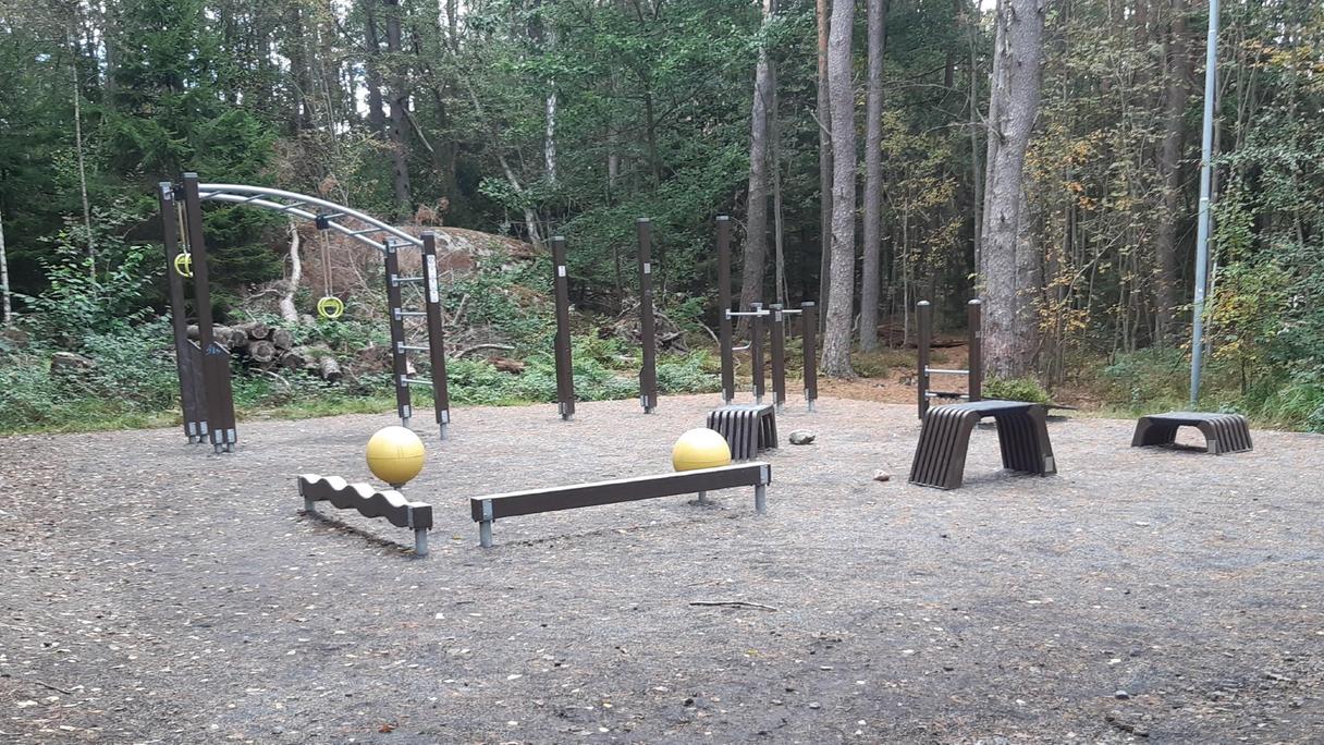 Utegym med grusat underlag med olika redskap i naturområde