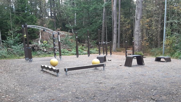 Utegym med grusat underlag med olika redskap i naturområde