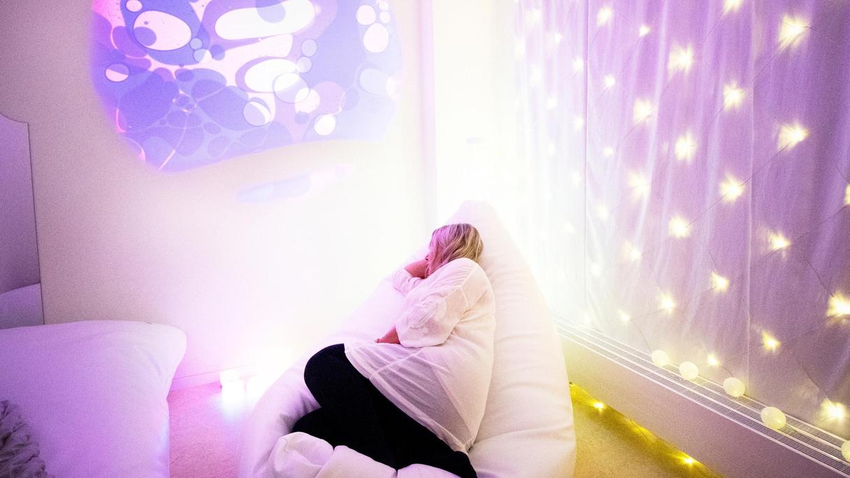 Person som ligger i ett rum med lila ljus
