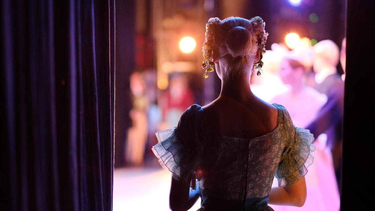 Ryggen på person med klänning på väg upp på en scen