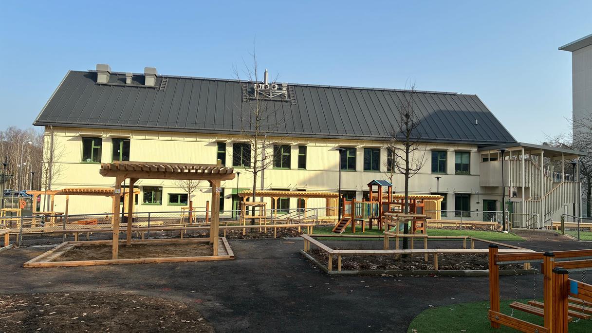 Förskolan Tellusgatans ljusa byggnad i två våningar med gården i förgrunden