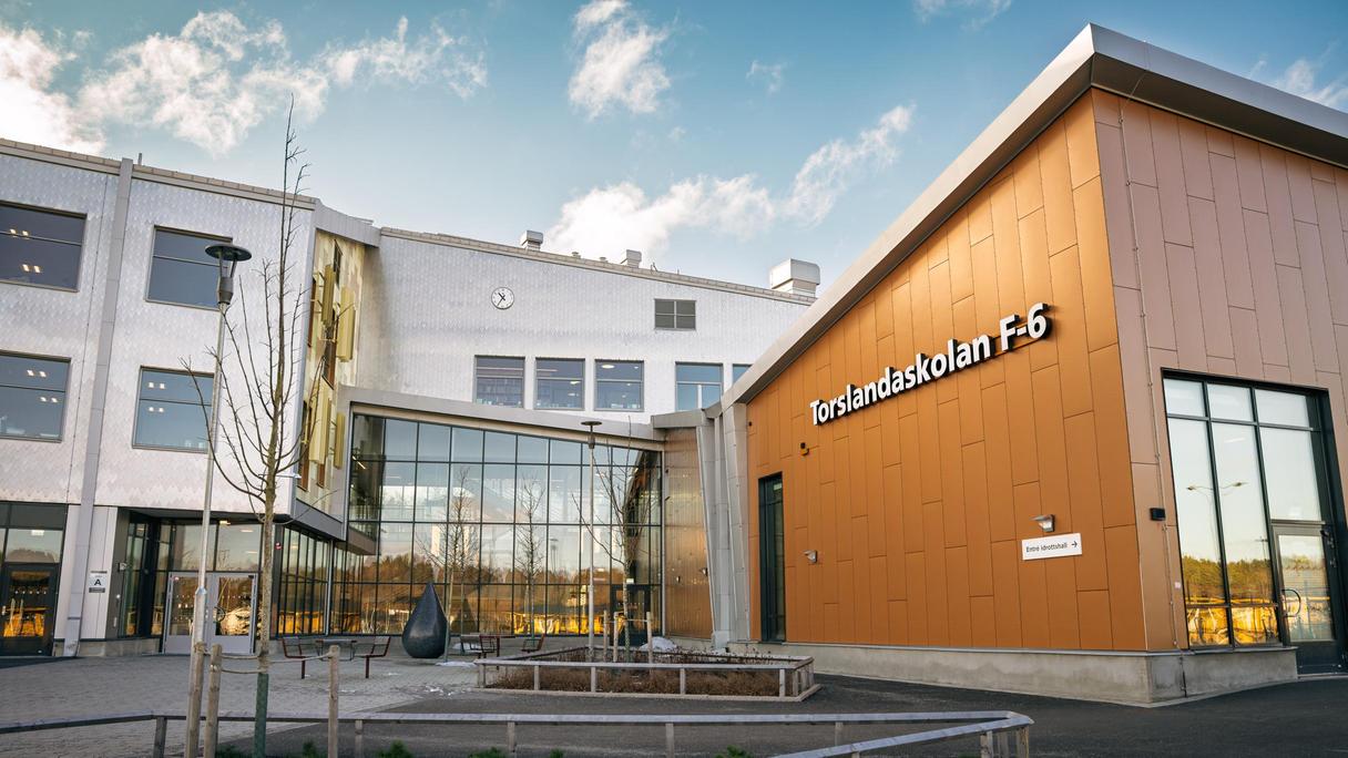 En skolbyggnad med texten Torslandaskolan F-6 på fasaden och en glasad entré