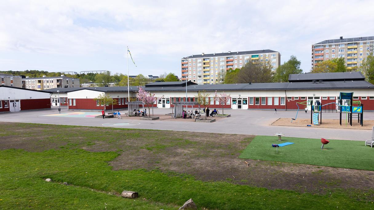 TretjärnsskolaI bakrunden syns olika lägenhetshus, solen skiner och på skolgården framför skolbyggnaden leker barn.
