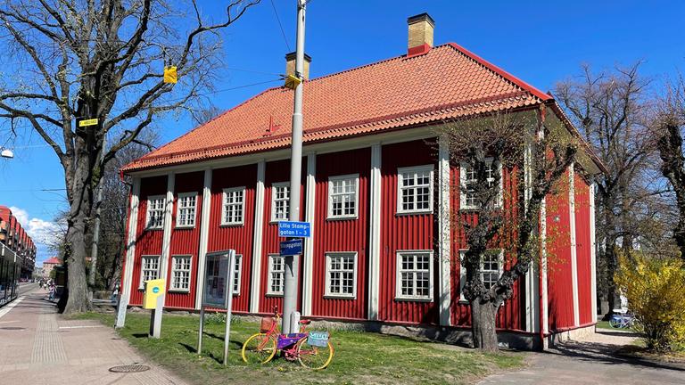 Röd träbyggnad intill spårvagnshållplats.