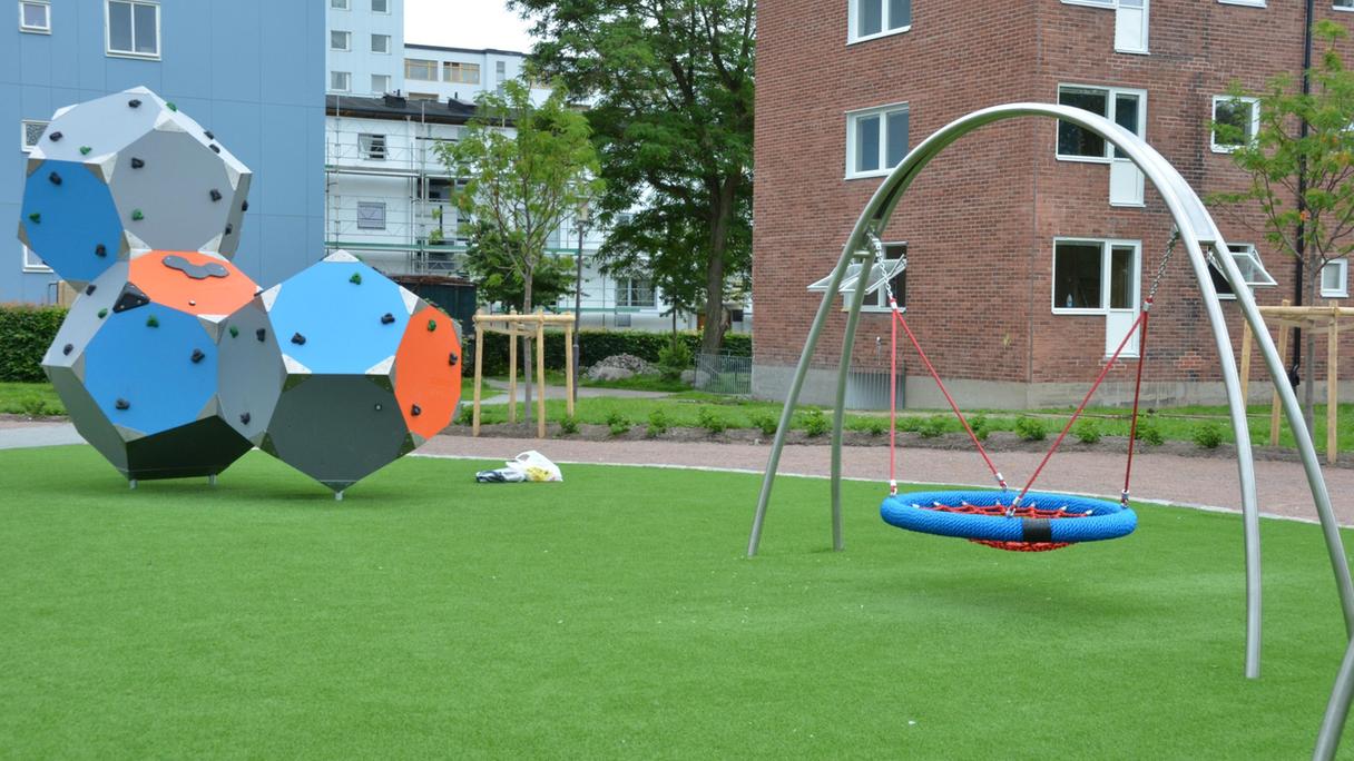 Yta av konstgräs med en klätterställning och en gungställning.