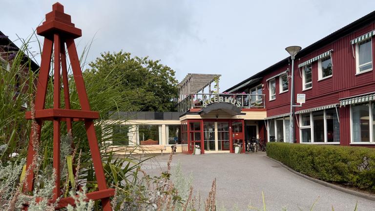En låg byggnad i en höstlik trädgård