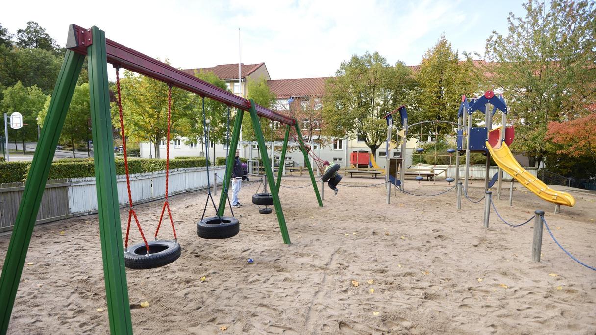 Yta av sand med en stor gungställning och klätterställning med rutschkana.