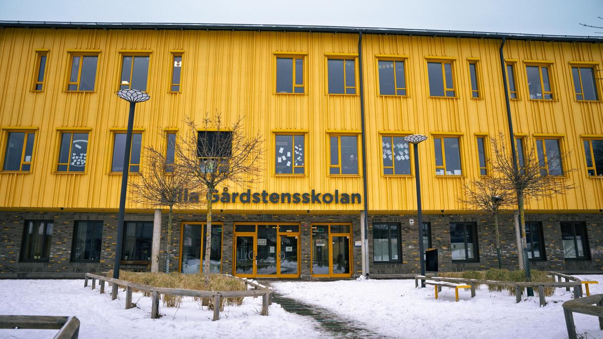 En stor gul skolbyggnad med texten Lilla Gårdstensskolan på fasaden